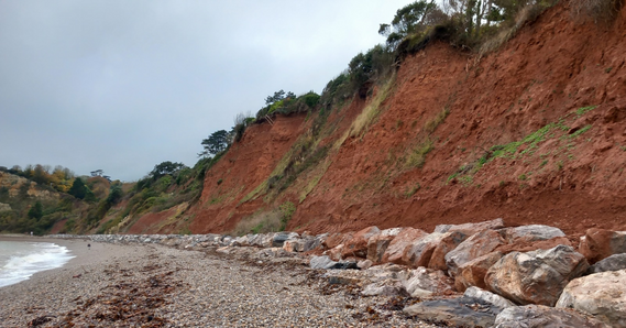 Seaton Hole Beach, with pebbles in the foreground, with rocks and cliff behind