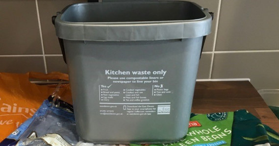 Food waste caddy on a kitchen worktop, on top of plastic bags