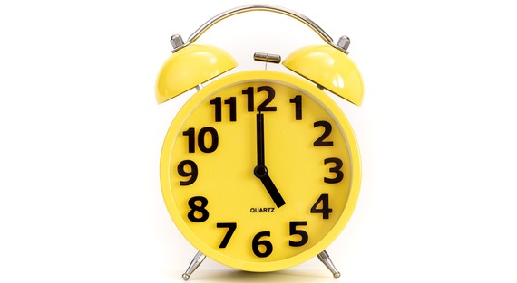 Yellow alarm clock showing the hands at 5 o'clock