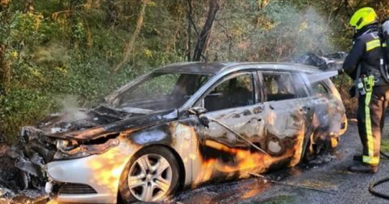 Car fire on side of road being extinguished