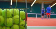 Tennis balls at a court, with people in the background