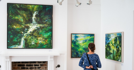 A person visiting the Yasmin David exhibition next to three artworks displayed on the gallery walls 