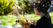 Child wearing a witch hat with stars on, holding an apple with berries and leaves attached