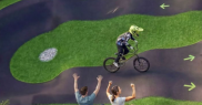 Person on a bike on a pump track and people cheering