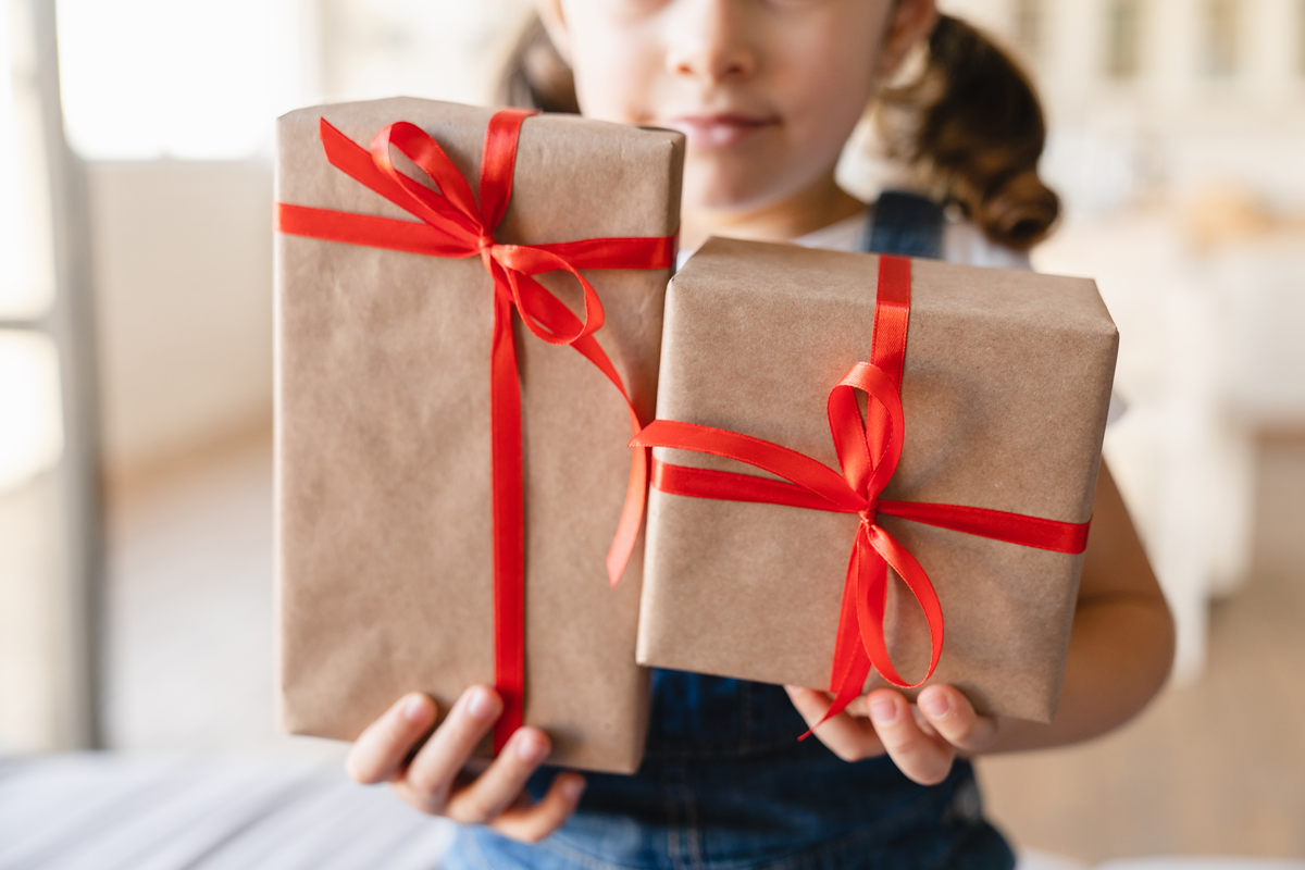 Girl carrying presents wrapped in brown paper