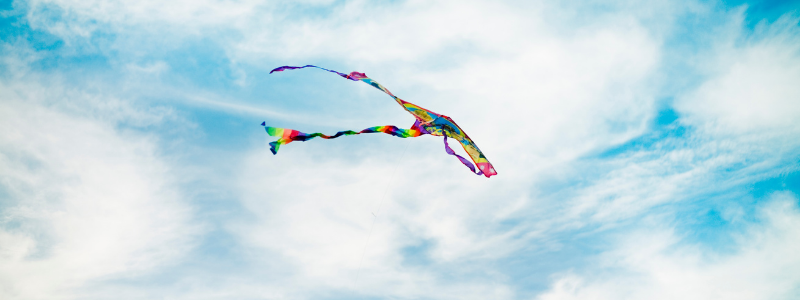 Colourful kite flying in a blue cloudy sky