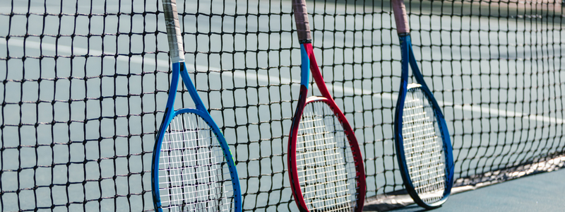 tennis rackets lined up against a tennis net