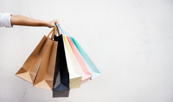 A hand holding up multi coloured shopping bags.