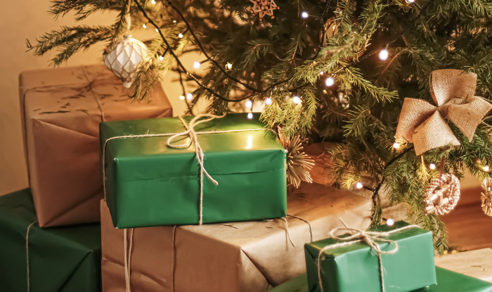 Sustainably wrapped Christmas presents placed under a Christmas tree.