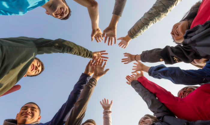 People in a circle putting there arms/hands in the middle