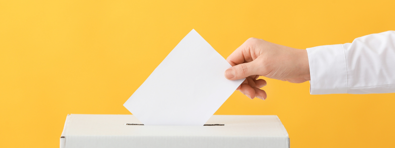 Hand posting ballot into box on yellow background