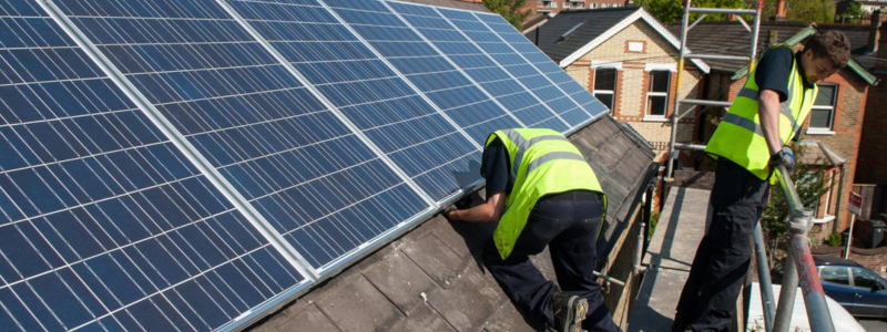 Two men installing solar panels on a roof