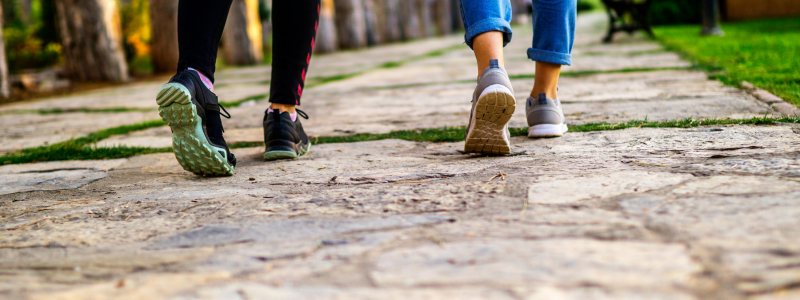 Feet of two people walking on a footpath