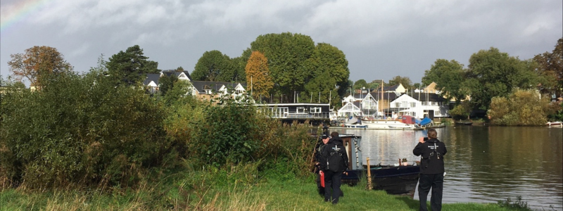 Police officers near a boat on the river