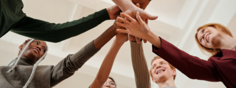 Five people putting their hands on top of each other in a circle