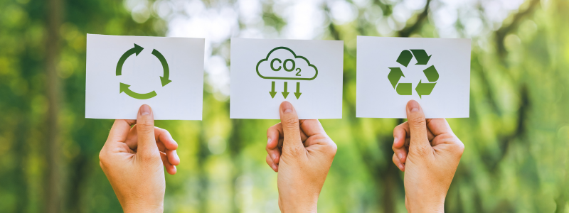 Hands holding paper with recycling, CO2 and reuse symbols