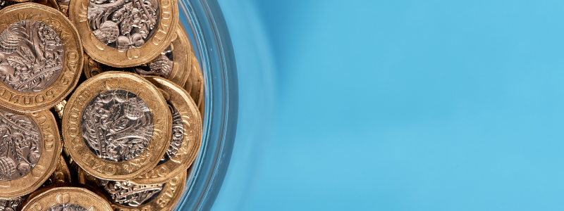 pounds coins in a glass jar on a blue background