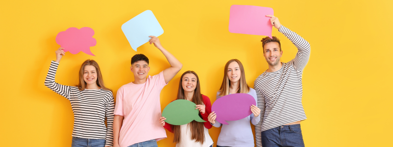 Five people stood holding up cut out speech bubbles