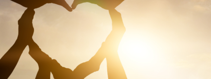 Arms making the shape of a heart with sunlight shining through