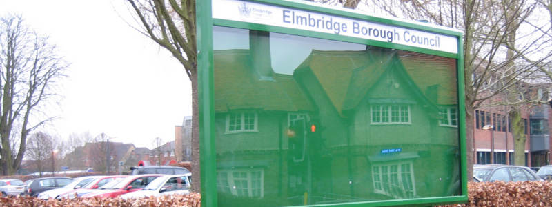 Elmbridge green noticeboard with cars in background