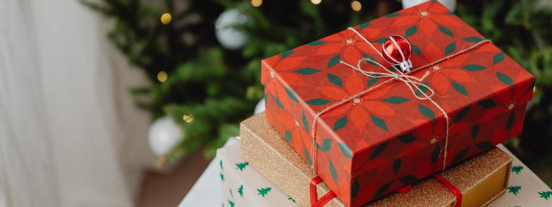Stack of christmas presents in front of a tree