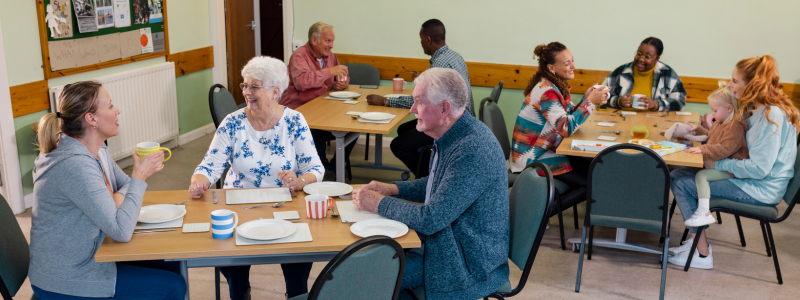 Image of a community centre with people sitting around a table
