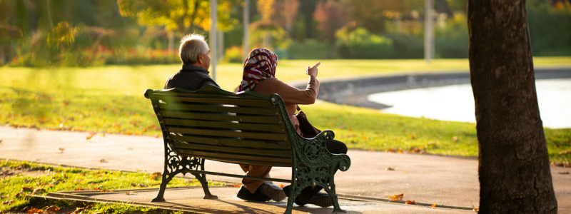 older couple sat on bench in park