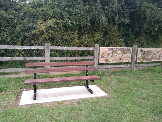 bench in grassy area in front of information boards