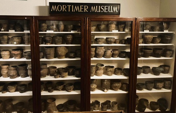 picture of large display cabinet with rows of shelves full of ancient pottery