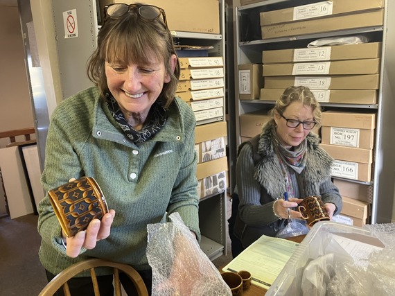 two volunteers sitting at a table examining pieces of Hornsea pottery