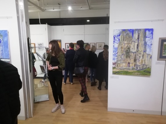 a group of people looking at paintings in an exhibition
