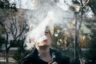 A photo of a young person vaping with the vape cloud covering their face