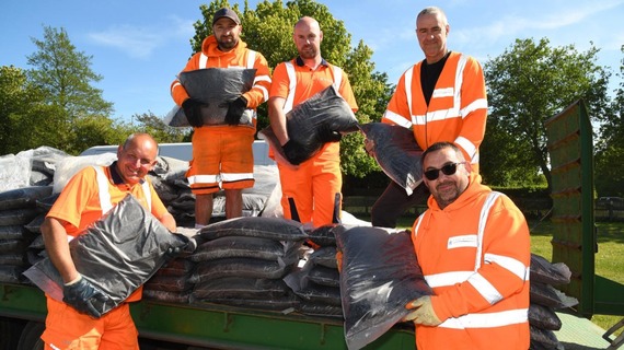 People wearing high-vis jackets and carrying bags of compost