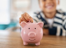 person putting money in a piggy bank