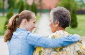 A photo of a young person with their arm around an elderly person