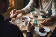 two people sitting opposite each other at a table in a cafe 