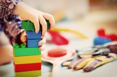 young child playing with green, blue, red and yellow blocks