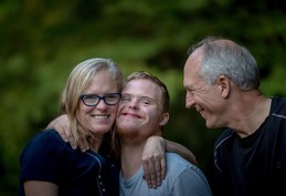 a young person shares a hug with two older people