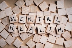 the words 'mental health' are spelt out using wooden scrabble tiles 