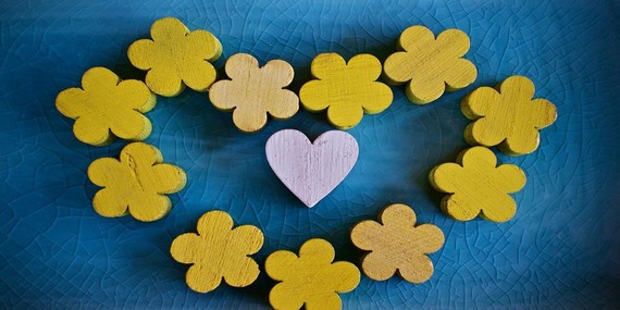 A blue background with yellow wooden flowers arranged in a heart shape
