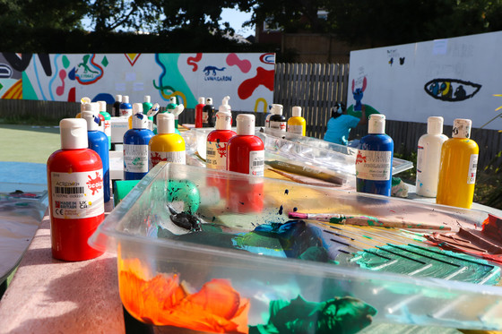A variety of red, yellow, green, blue, black and white paints on a table at the SEND Art Mural Project Summer 2022.