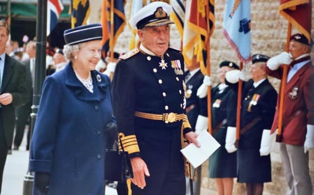 The Queen walks beside a man in uniform