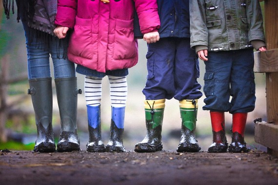 A group of children are holding hands and wearing muddy welly boots