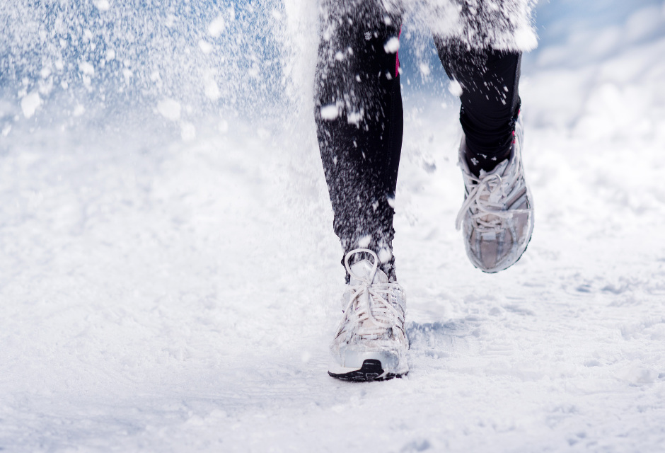 The view of someone's legs and trainers as they run in the snow