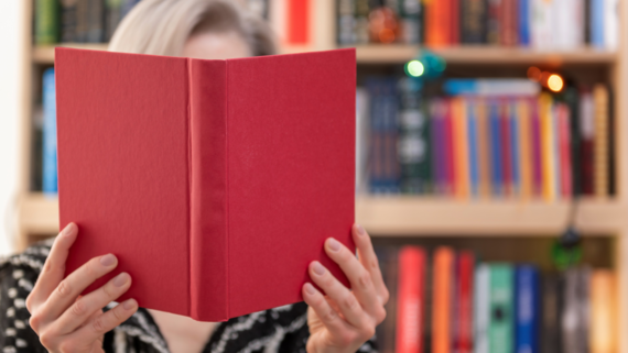 Person holding book in front of face