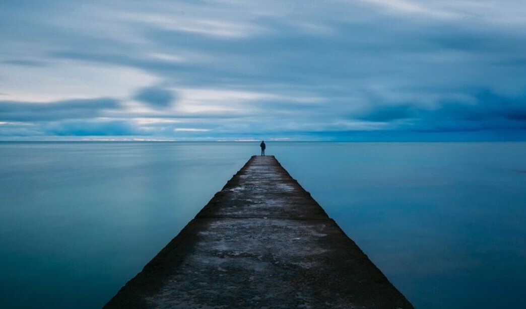image of person on a jetty looking out to water