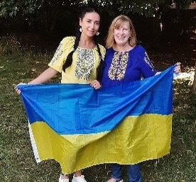 Natallia and Debbie standing in front of a Ukrainian flag