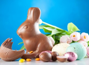 Chocolate rabbit and Easter eggs with pink flowers in background