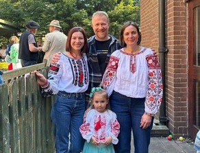 THree adults and a small child smiling at the camera. They are wearing Ukrainian dress