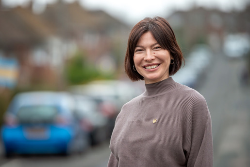 Woman in fawn-coloured jumper smiles at camera